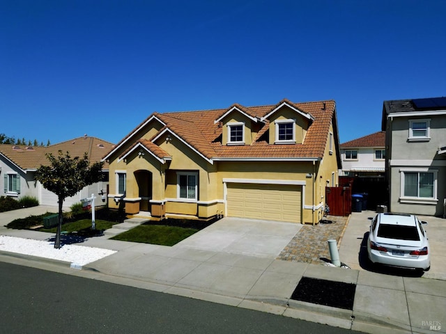 view of front of property with a tile roof, driveway, fence, a garage, and stucco siding