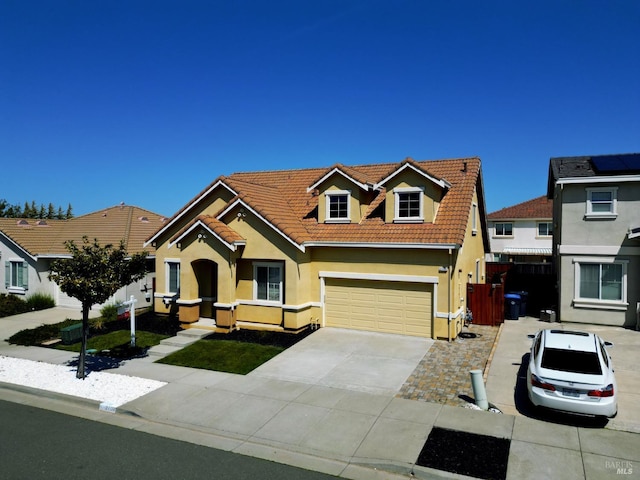 view of front facade with concrete driveway, a tile roof, an attached garage, and stucco siding