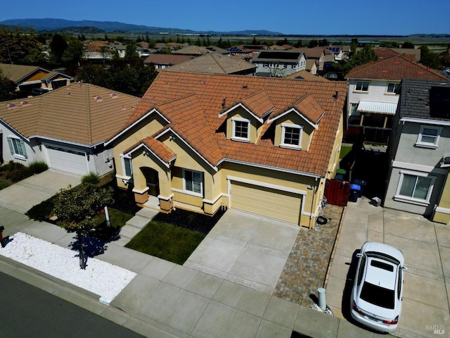 view of front of home featuring an attached garage, a tiled roof, driveway, and a residential view