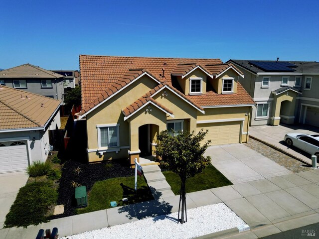 view of front of property with a tile roof, an attached garage, driveway, and stucco siding