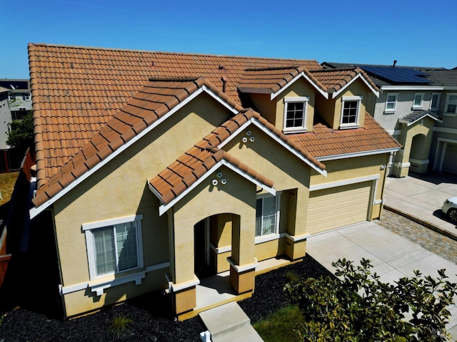view of front of house featuring a tiled roof, driveway, and stucco siding