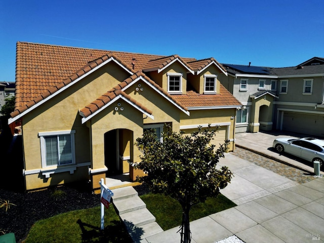 view of front of house with a tiled roof, an attached garage, stucco siding, and concrete driveway