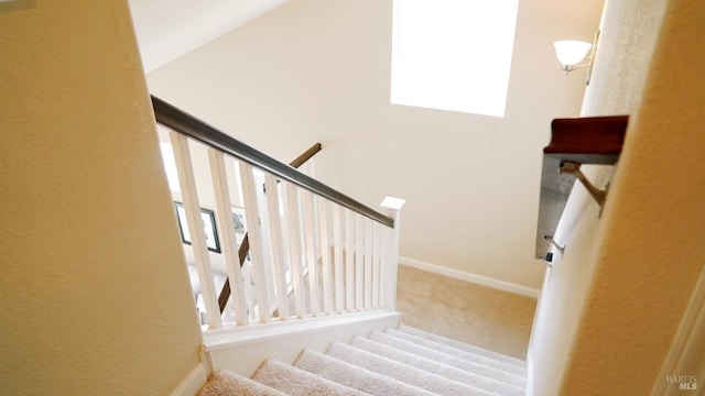stairway featuring baseboards and carpet floors