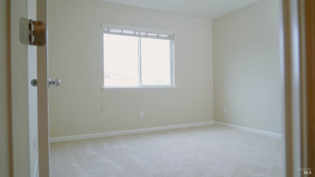 unfurnished room featuring baseboards and light carpet