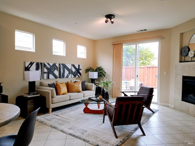 living area featuring a tile fireplace, light tile patterned floors, visible vents, and a healthy amount of sunlight