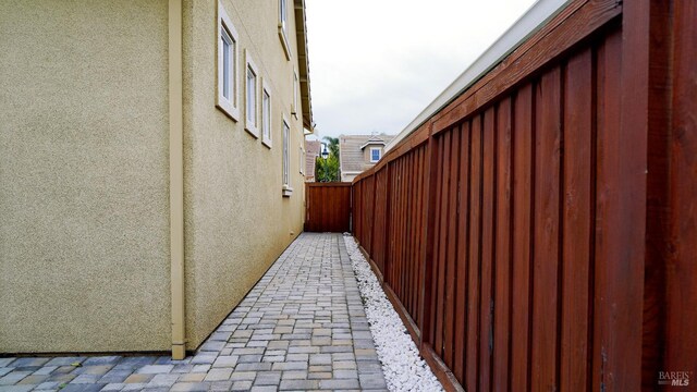view of side of home with fence and stucco siding