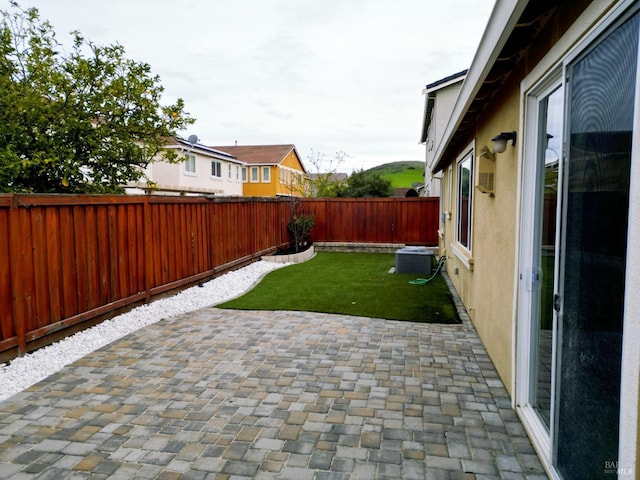 view of yard with a patio area, a fenced backyard, and central AC