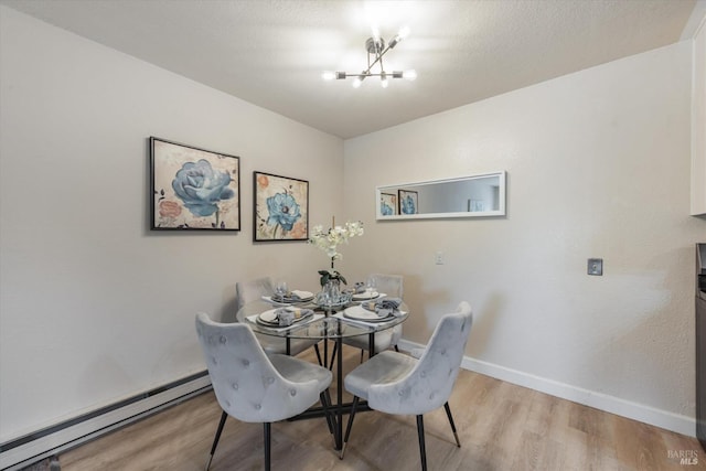 dining room featuring a chandelier, a textured ceiling, a baseboard radiator, baseboards, and light wood-style floors