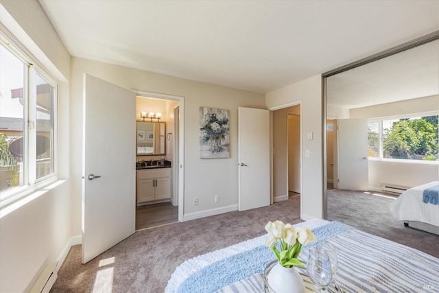 bedroom featuring baseboards, connected bathroom, light colored carpet, baseboard heating, and a baseboard heating unit