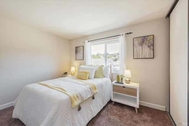 bedroom featuring dark carpet and baseboards