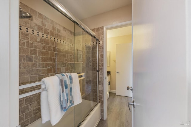 full bath with bath / shower combo with glass door, wood finished floors, and vanity