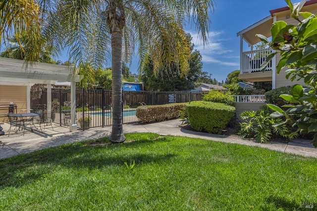 view of yard with a balcony, a patio area, fence, and a fenced in pool