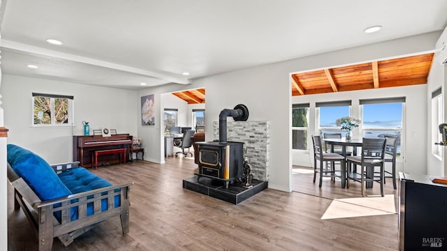 living area featuring a wood stove, lofted ceiling with beams, wood finished floors, and recessed lighting