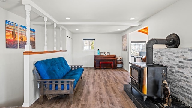 sitting room with recessed lighting, wood finished floors, baseboards, beamed ceiling, and a wood stove