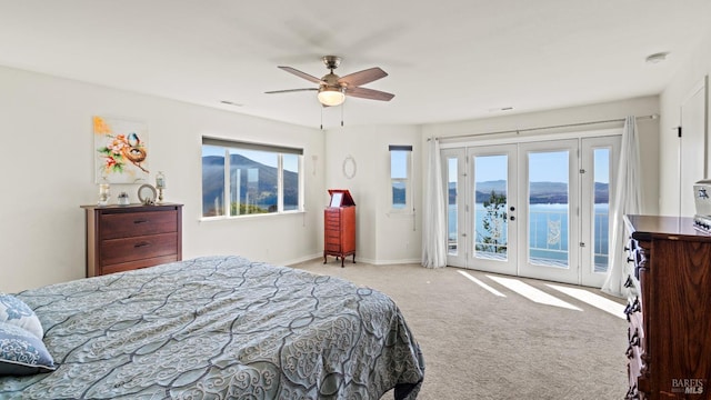 bedroom with light carpet, a water view, access to outside, french doors, and multiple windows