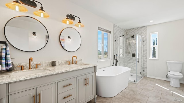 full bathroom with double vanity, a stall shower, a freestanding tub, and a sink