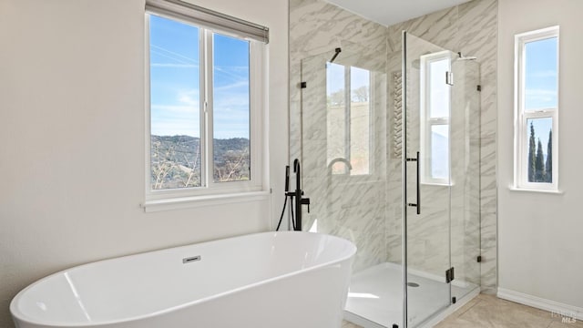 full bath featuring a soaking tub, a shower stall, and baseboards