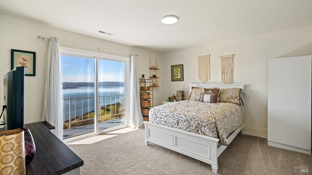 bedroom with carpet floors, a water view, visible vents, and access to exterior