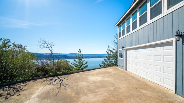 exterior space featuring an attached garage, a water and mountain view, and concrete driveway