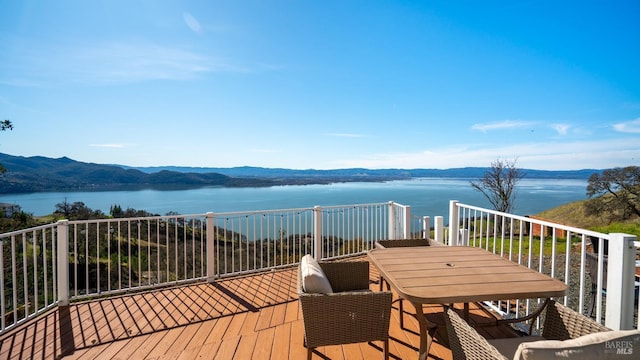 wooden terrace featuring outdoor dining area and a water and mountain view