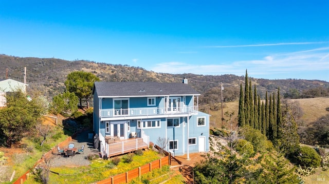 rear view of property with a mountain view, french doors, fence, and a balcony