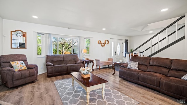 living room featuring baseboards, stairway, light wood-type flooring, and recessed lighting