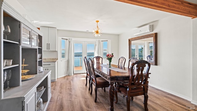 dining room with french doors, a wall mounted air conditioner, wood finished floors, and baseboards