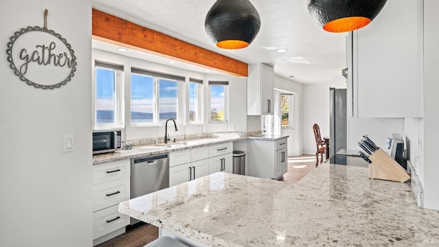 kitchen featuring light stone countertops, white cabinetry, appliances with stainless steel finishes, and a sink