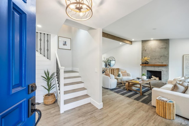 foyer entrance featuring stairs, lofted ceiling with beams, a fireplace, and light wood-style flooring