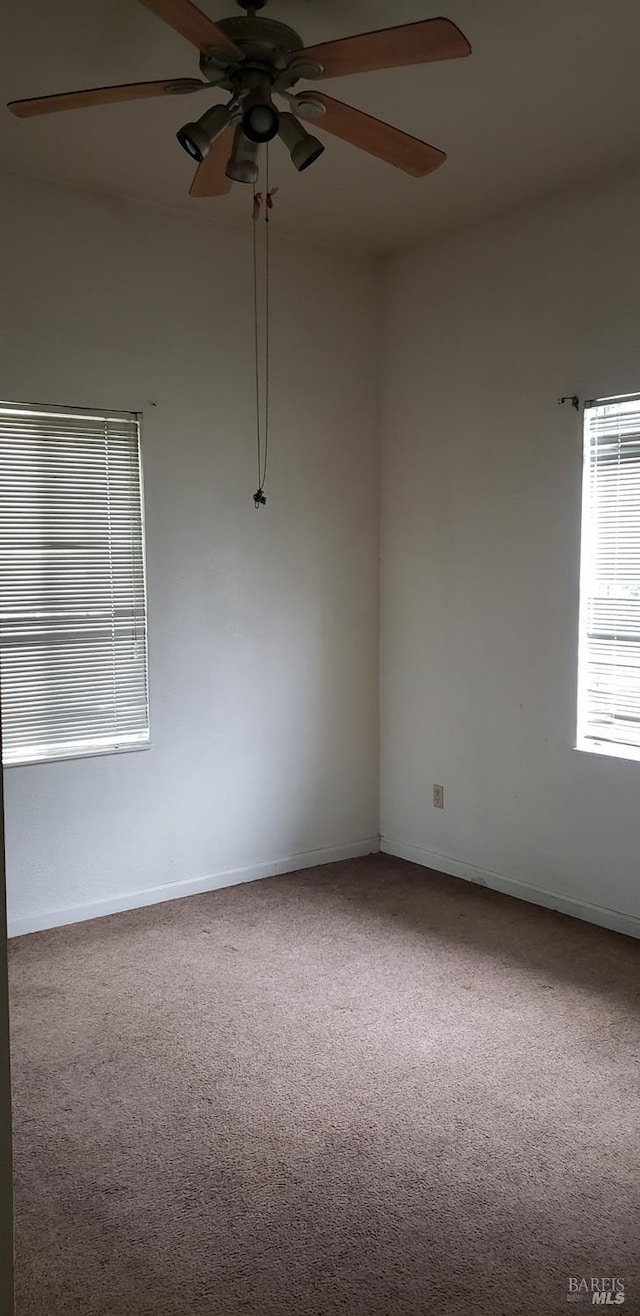 carpeted spare room with ceiling fan and baseboards