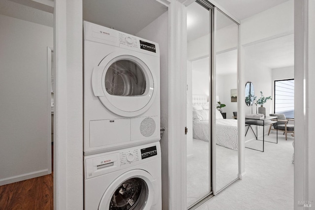 laundry room with laundry area, wood finished floors, and stacked washer and clothes dryer