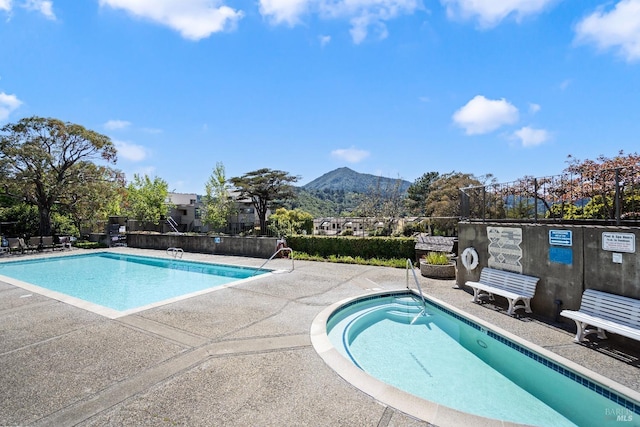 pool featuring a patio, fence, and a mountain view