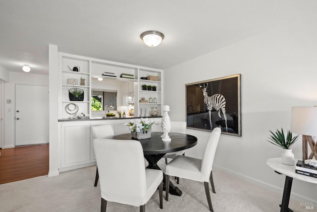 dining area featuring light carpet and baseboards