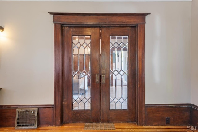 details with french doors, visible vents, a wainscoted wall, and wood finished floors