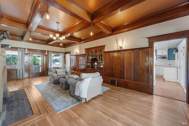 living area featuring light wood finished floors, visible vents, coffered ceiling, a notable chandelier, and beam ceiling