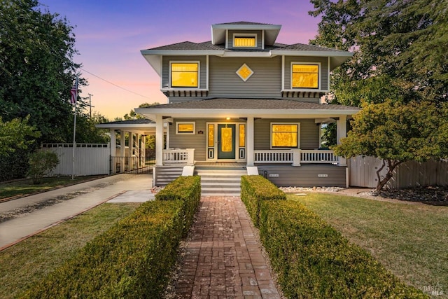 american foursquare style home with an attached carport, covered porch, fence, concrete driveway, and a front yard