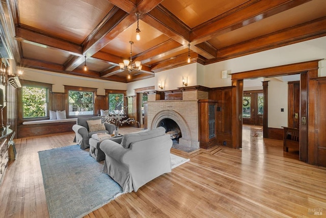 living area with light wood-type flooring, coffered ceiling, a fireplace, and beamed ceiling