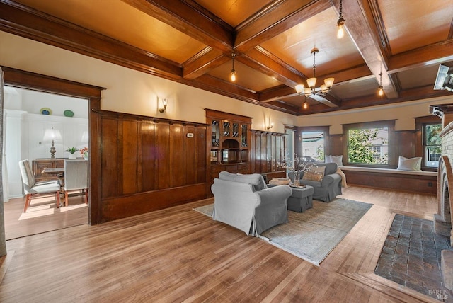 living room featuring an inviting chandelier, coffered ceiling, and light wood-style floors