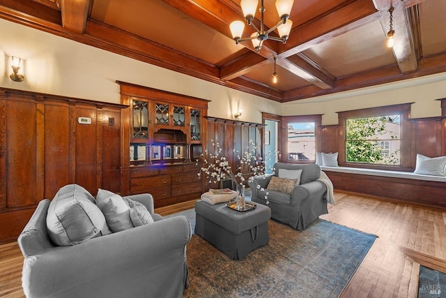 living area with coffered ceiling, a wainscoted wall, beamed ceiling, wood finished floors, and an inviting chandelier