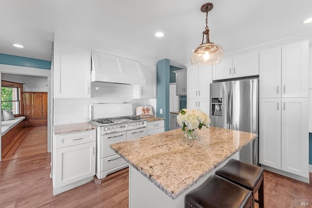 kitchen with range with two ovens, custom range hood, a center island, decorative light fixtures, and white cabinetry