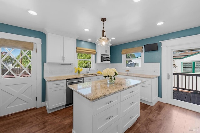 kitchen featuring dishwasher, a center island, decorative light fixtures, white cabinetry, and a sink