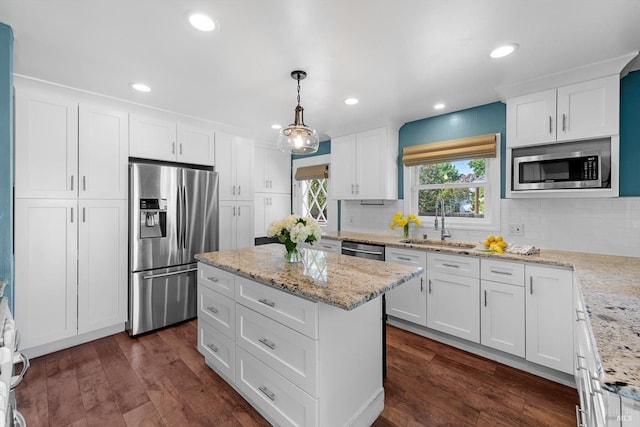 kitchen with appliances with stainless steel finishes, white cabinets, dark wood-type flooring, and decorative light fixtures