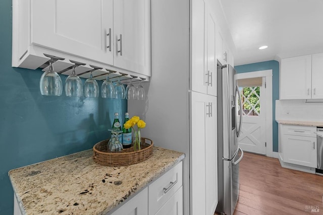 kitchen featuring light stone countertops, white cabinetry, and stainless steel refrigerator with ice dispenser