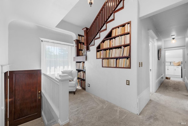 corridor with a wainscoted wall and light colored carpet