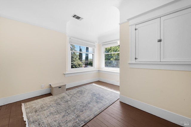 unfurnished room with baseboards, visible vents, and dark wood-type flooring