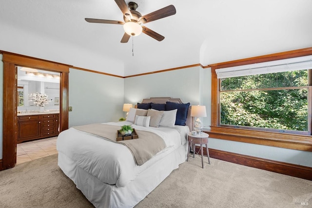 bedroom featuring a ceiling fan, light carpet, connected bathroom, and light tile patterned floors