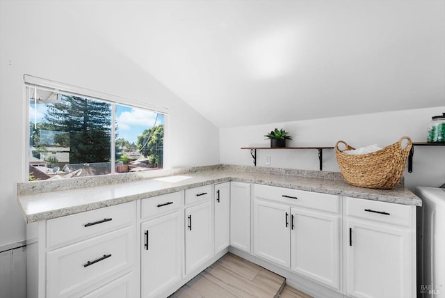 kitchen featuring vaulted ceiling, open shelves, light wood-type flooring, and white cabinetry