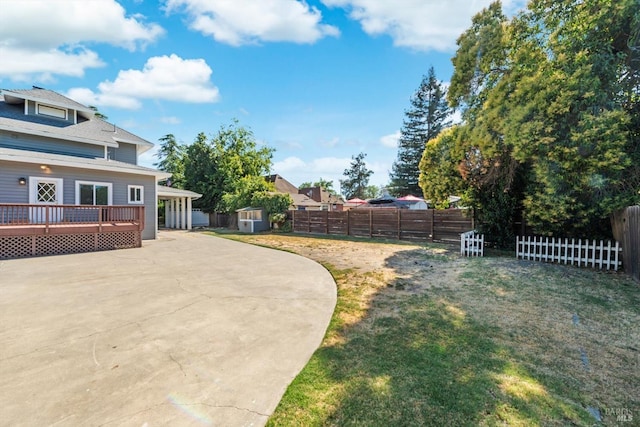 view of yard featuring a storage shed, a deck, an outdoor structure, and a fenced backyard