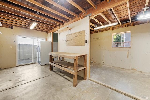 basement featuring stainless steel fridge with ice dispenser and a workshop area