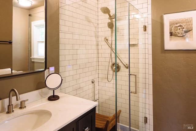 full bath with a stall shower, a textured wall, and vanity